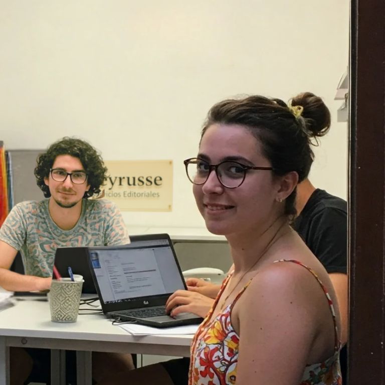 Miembros del equipo de servicios editoriales Equipo de trabajo reunido en la oficina de Peyrusse Servicios Editoriales, frente a portátiles y materiales de edición.